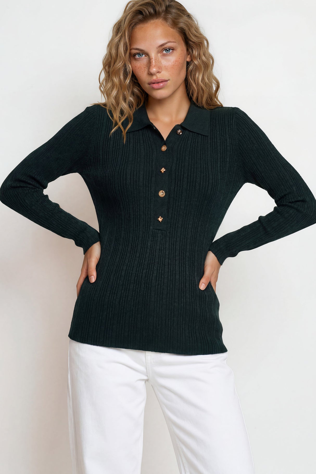 Woman wearing a black ribbed sweater with button details against a white background