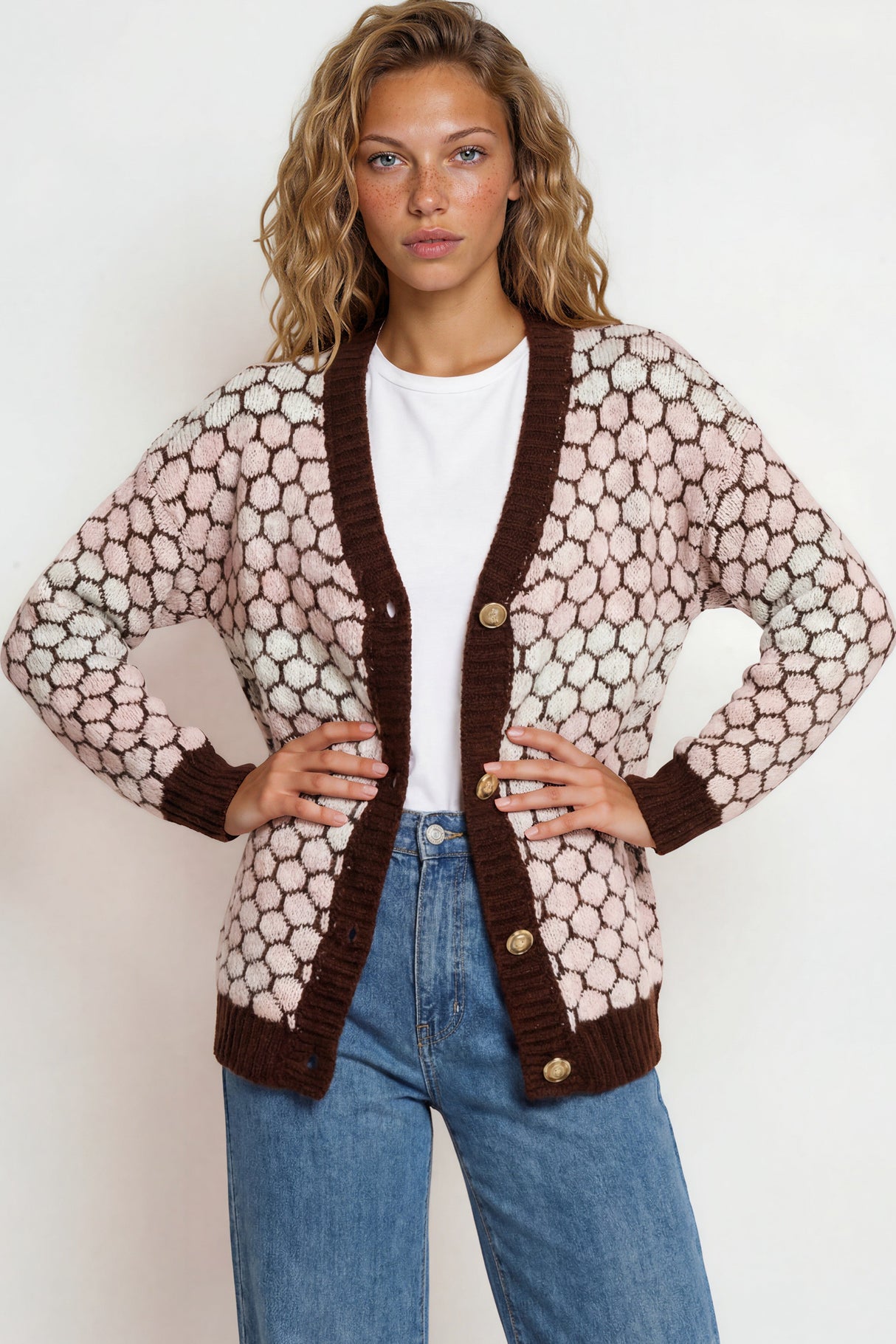 Woman wearing a patterned cardigan over a white shirt and blue jeans on a white background
