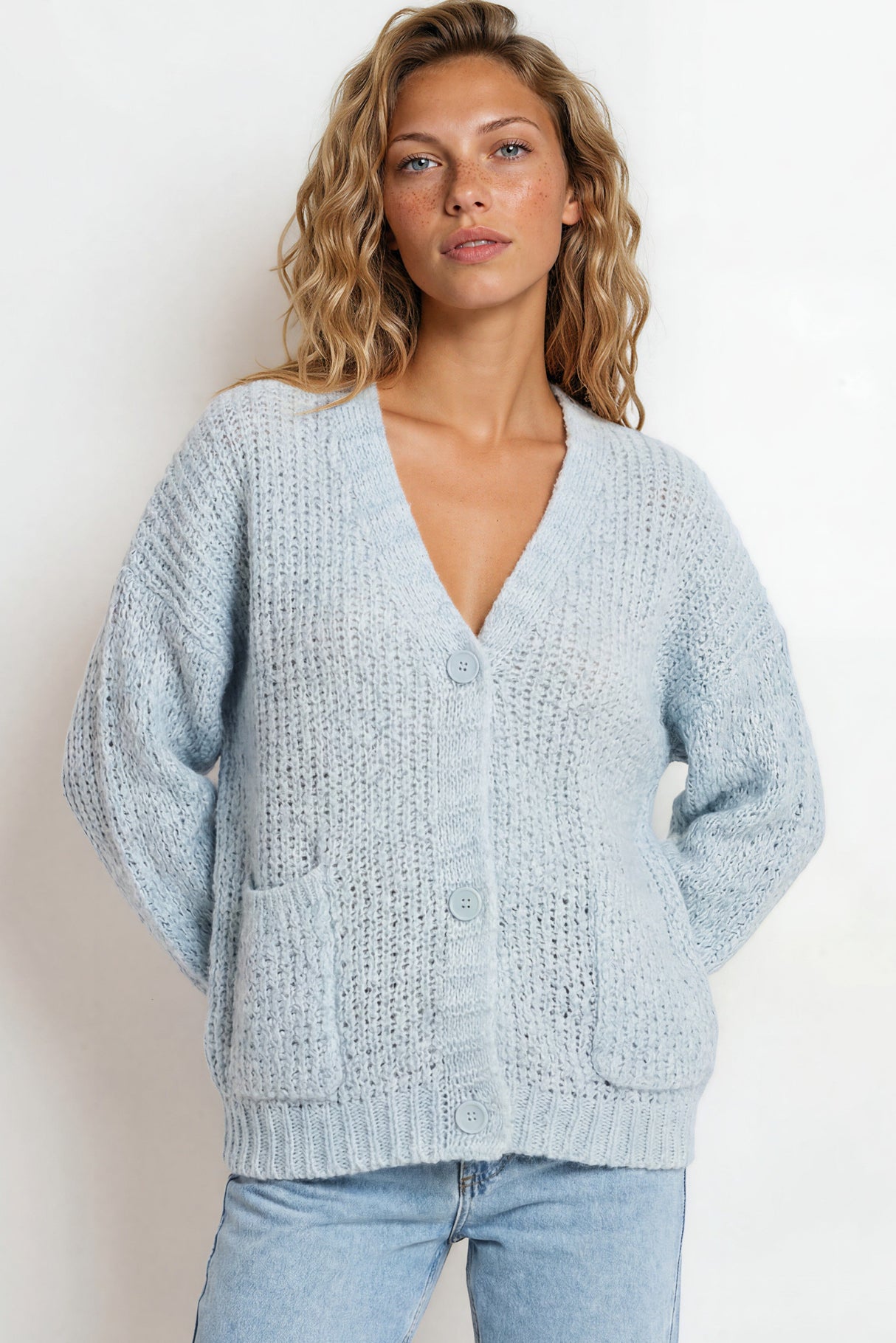 Woman wearing a light blue textured cardigan against a white background