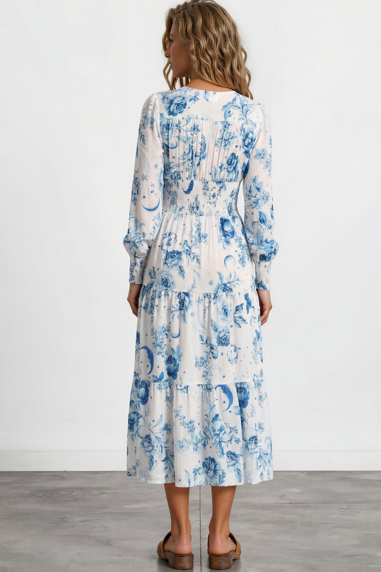 Woman wearing a white dress with blue floral pattern on a plain background