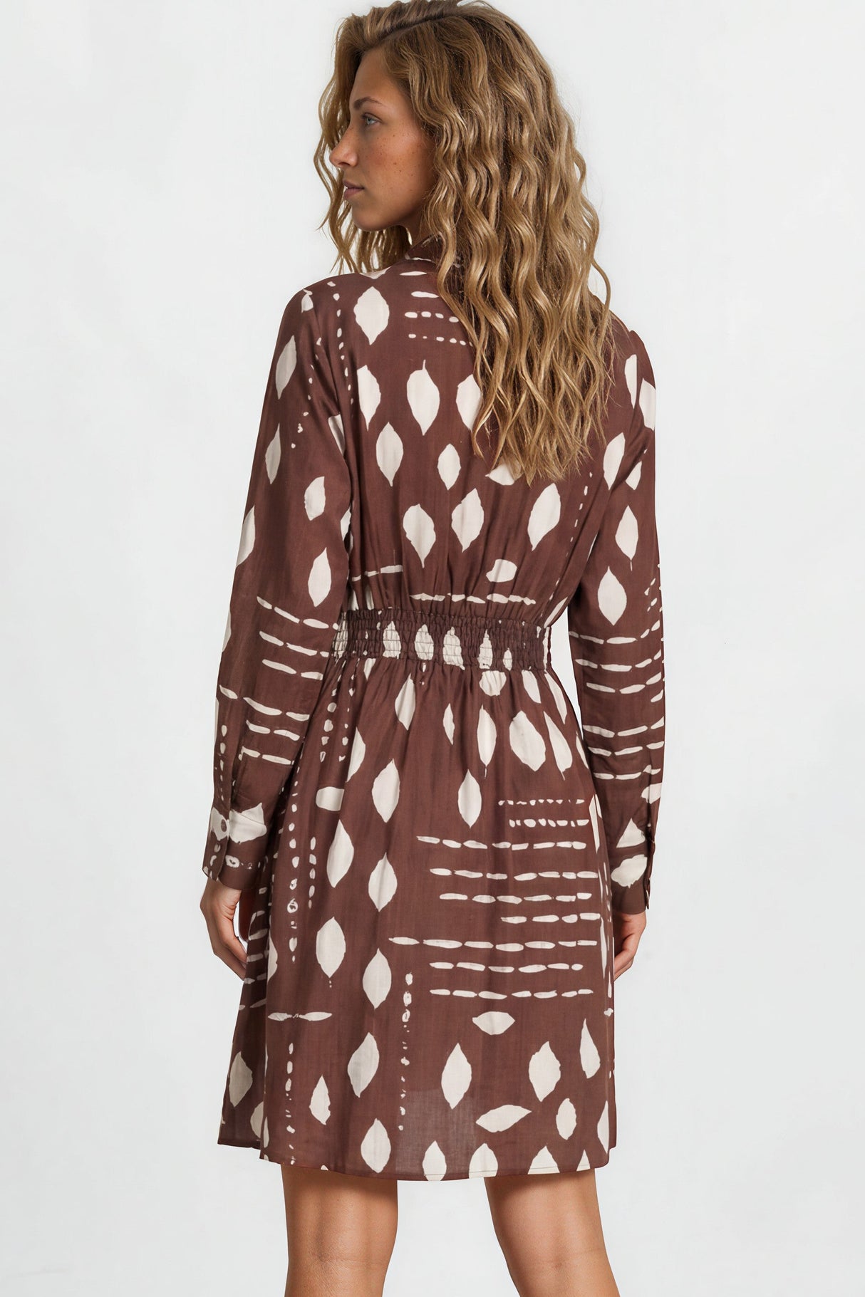 Woman wearing a patterned dress standing against a white background
