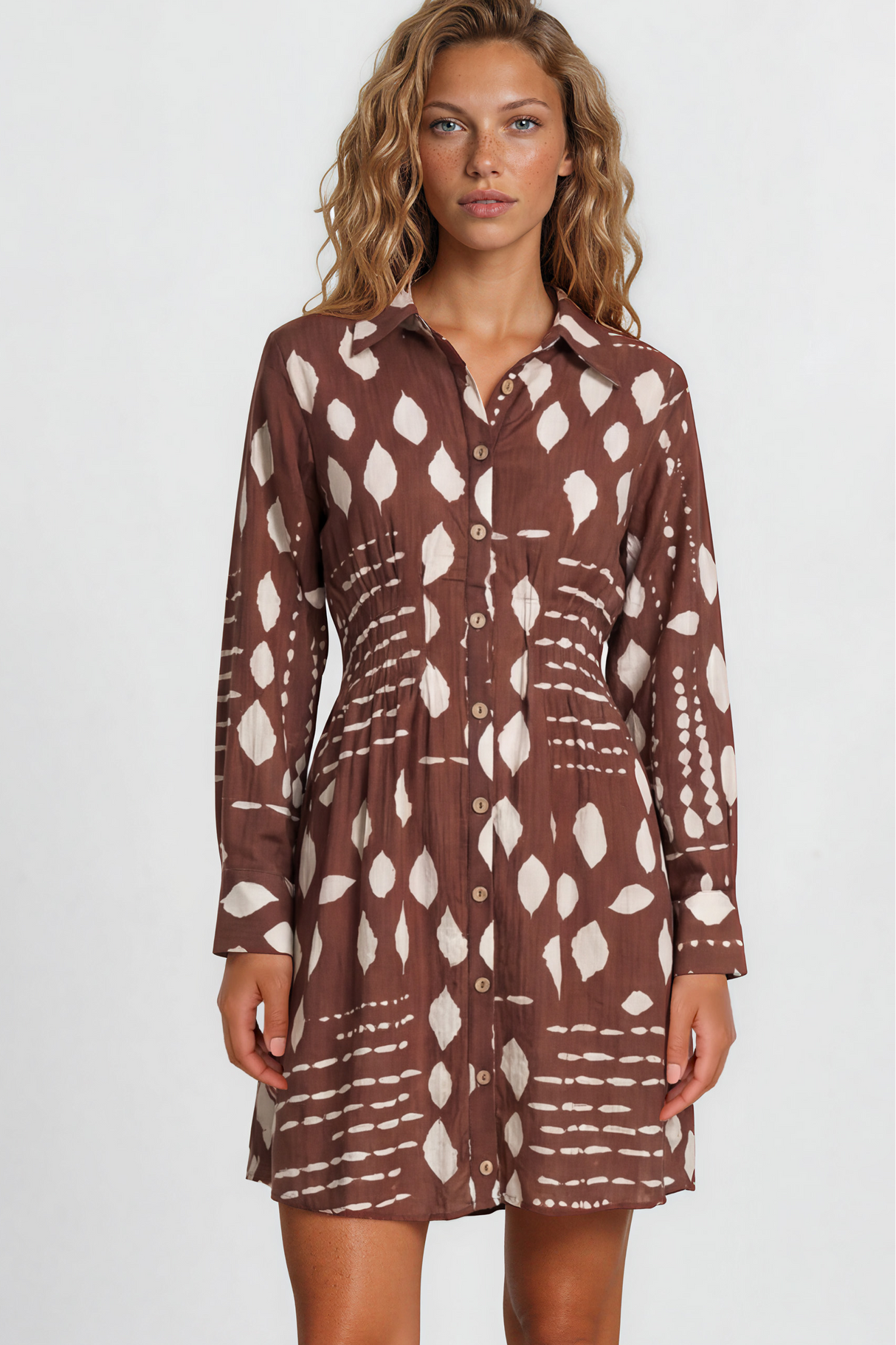 Woman wearing a brown patterned dress on a plain background