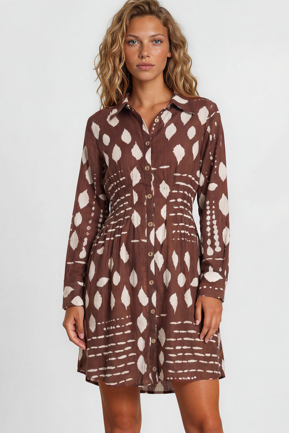Woman wearing a brown patterned dress standing against a white background