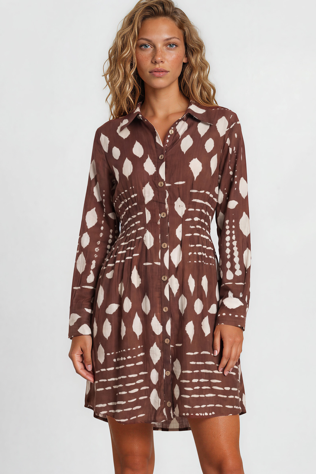 Woman wearing a brown patterned dress standing against a white background
