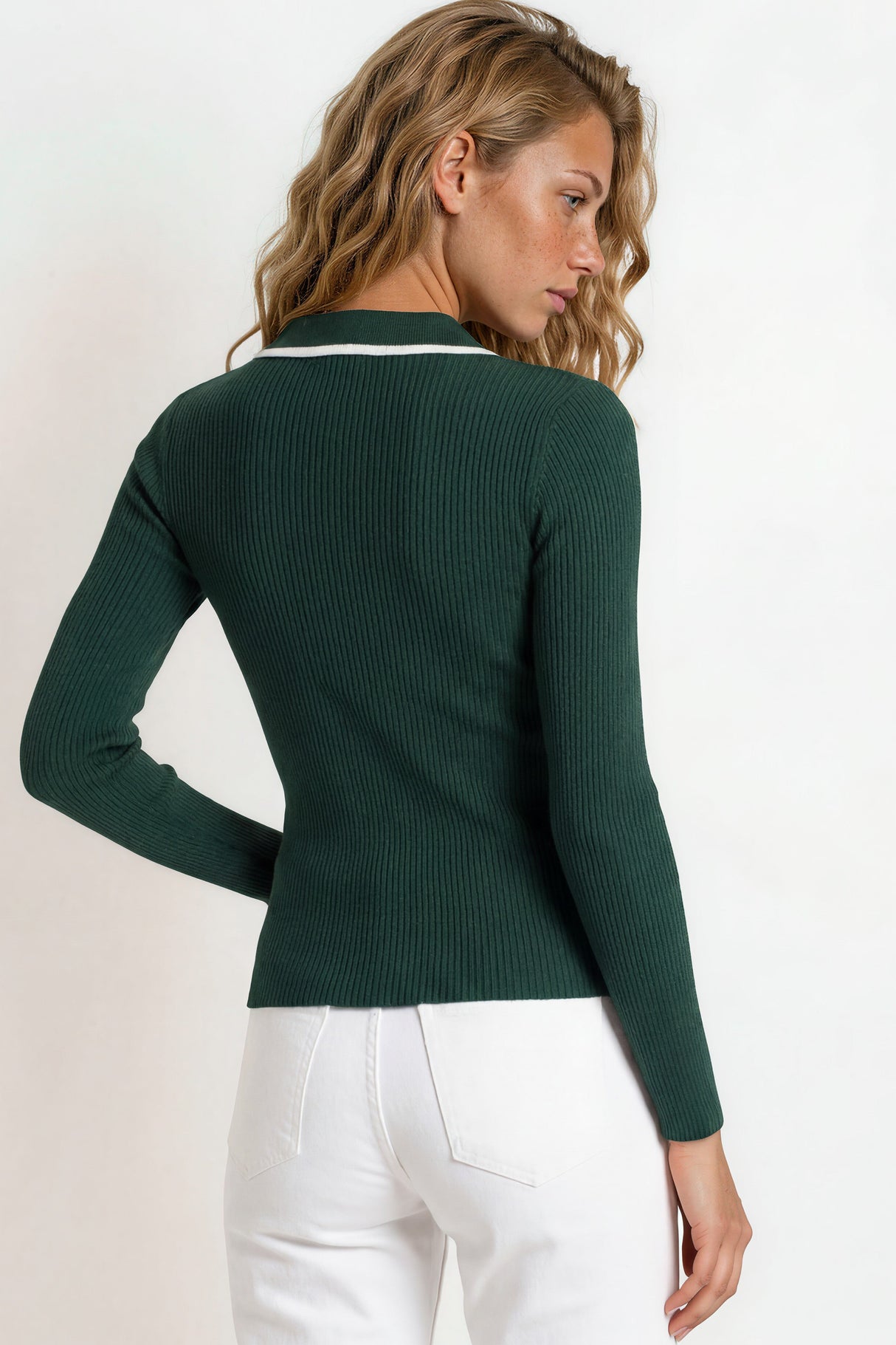 Woman wearing a green sweater with a white collar against a light background