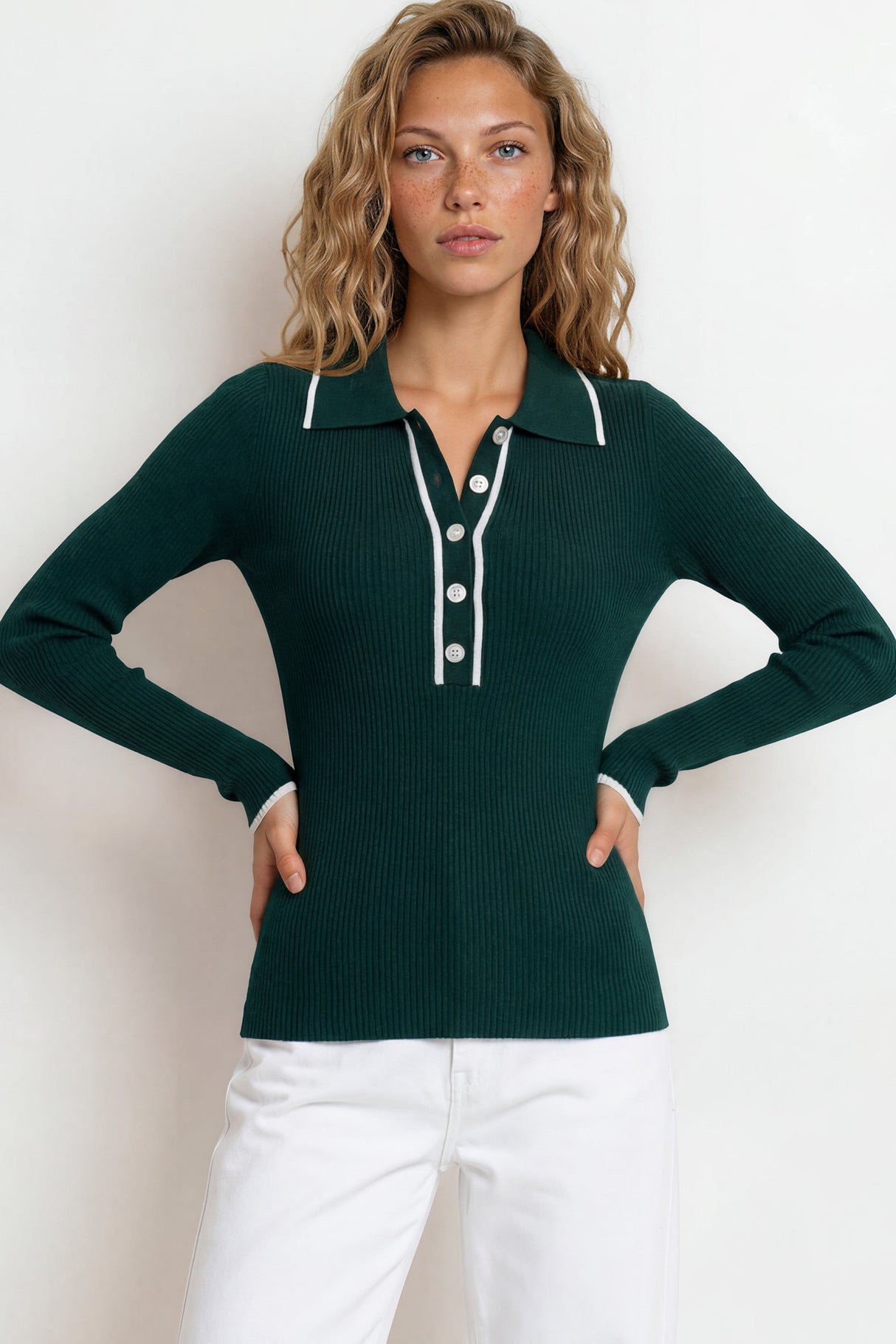 Woman wearing a green long-sleeve polo shirt with white buttons against a plain background