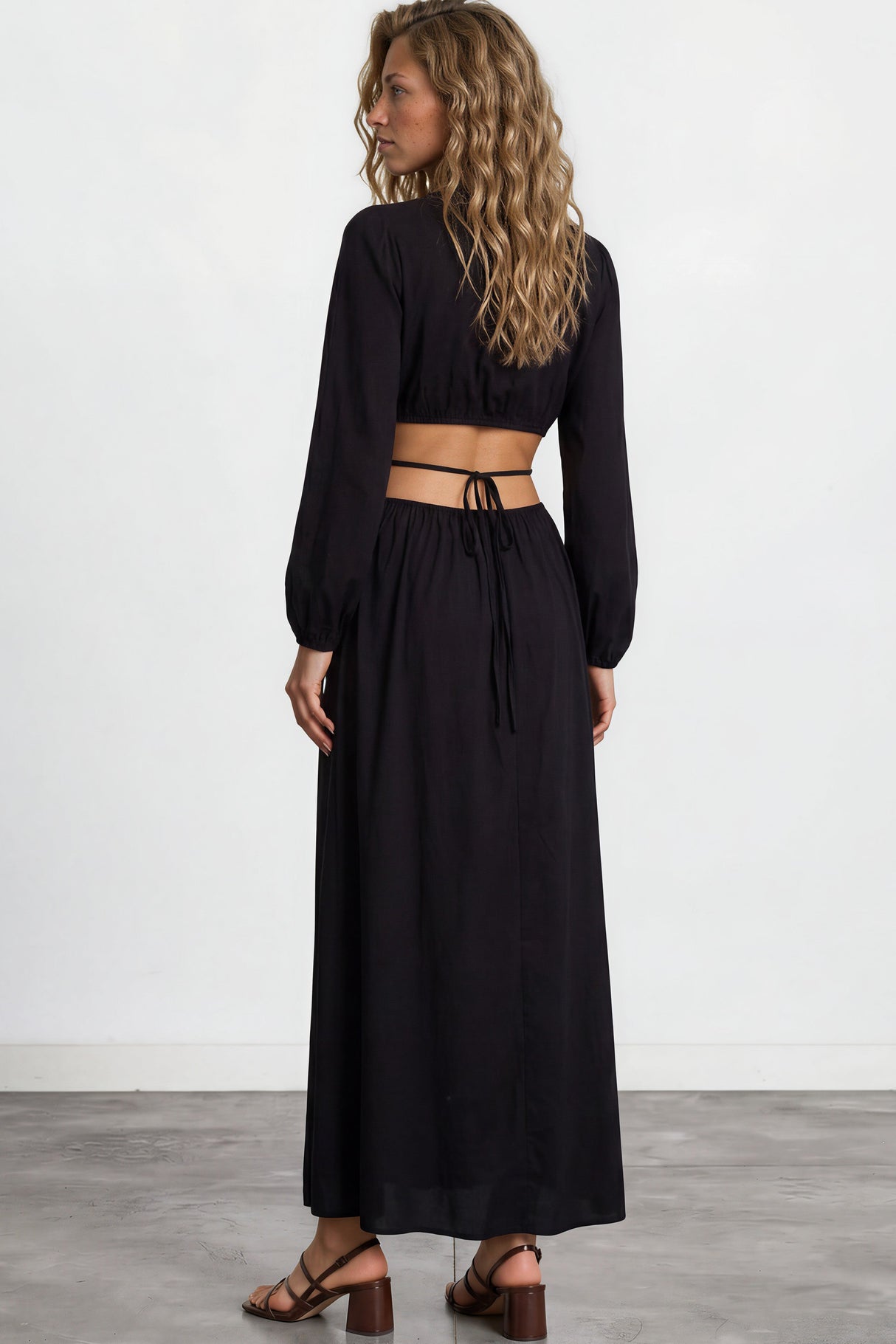 Woman wearing a black long-sleeve top and black skirt on a white background