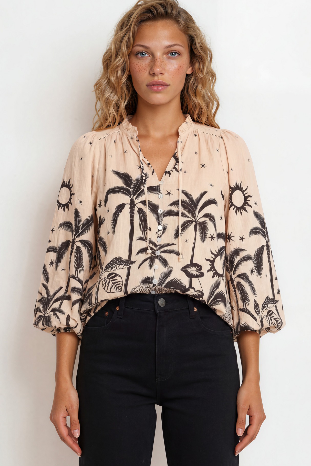 Woman wearing a blouse with palm tree pattern against a plain background
