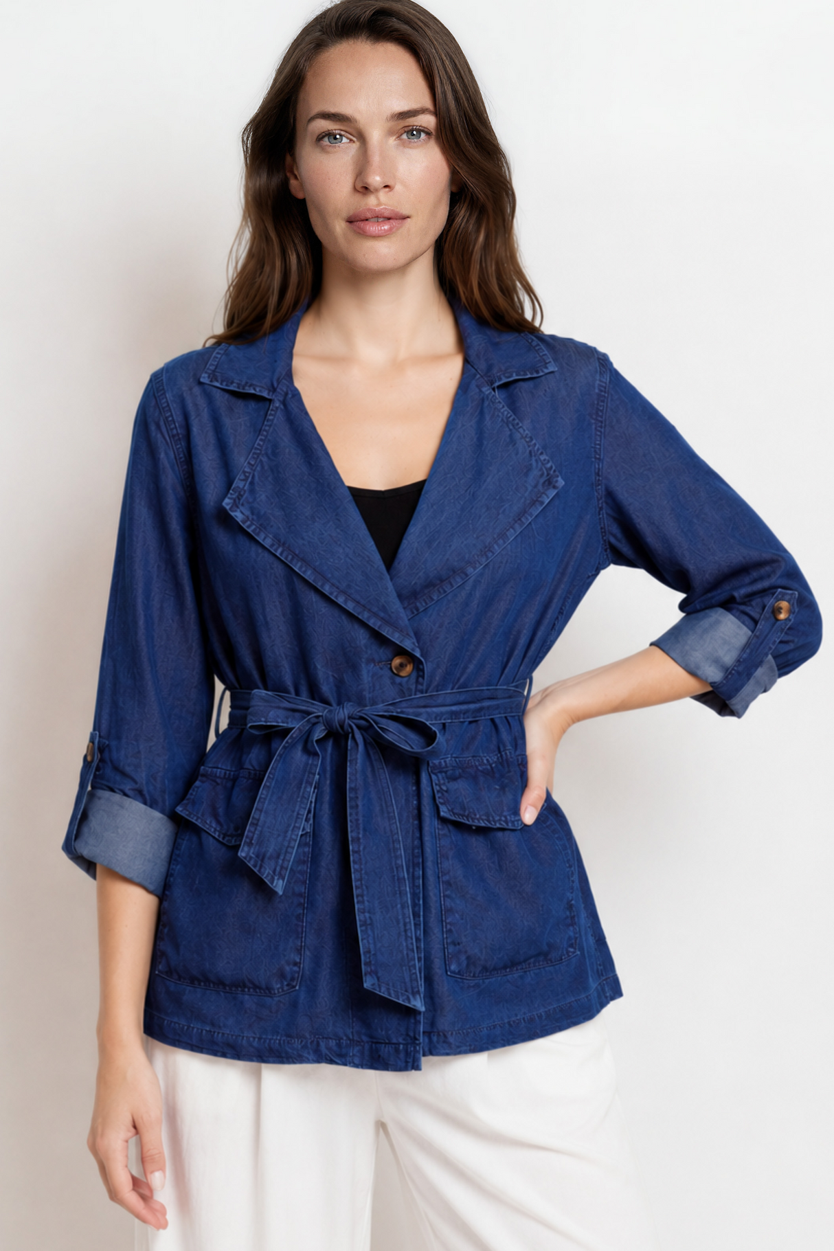 Woman wearing a blue jacket with a belt against a white background