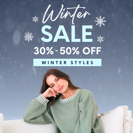 A woman wearing a light sage green knit sweater with white striped trim sits on a white couch against a snowy blue-gray background. Large promotional text reads 'Winter SALE 30%-50% OFF' and 'WINTER STYLES'.