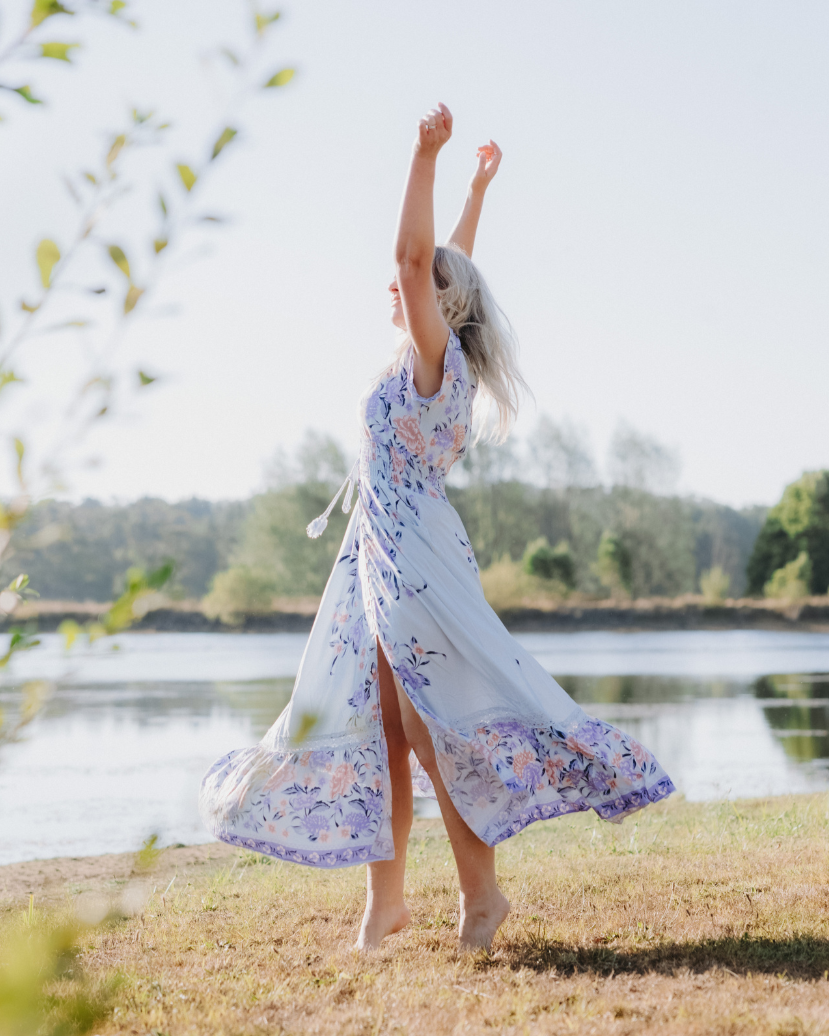 A woman wears a Salty Crush dress on the banks of a river