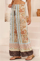 Person wearing a patterned wide-leg pants standing on a white staircase.
