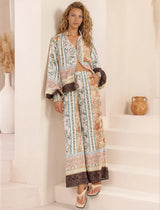 Woman wearing a long, patterned dress standing on a staircase.