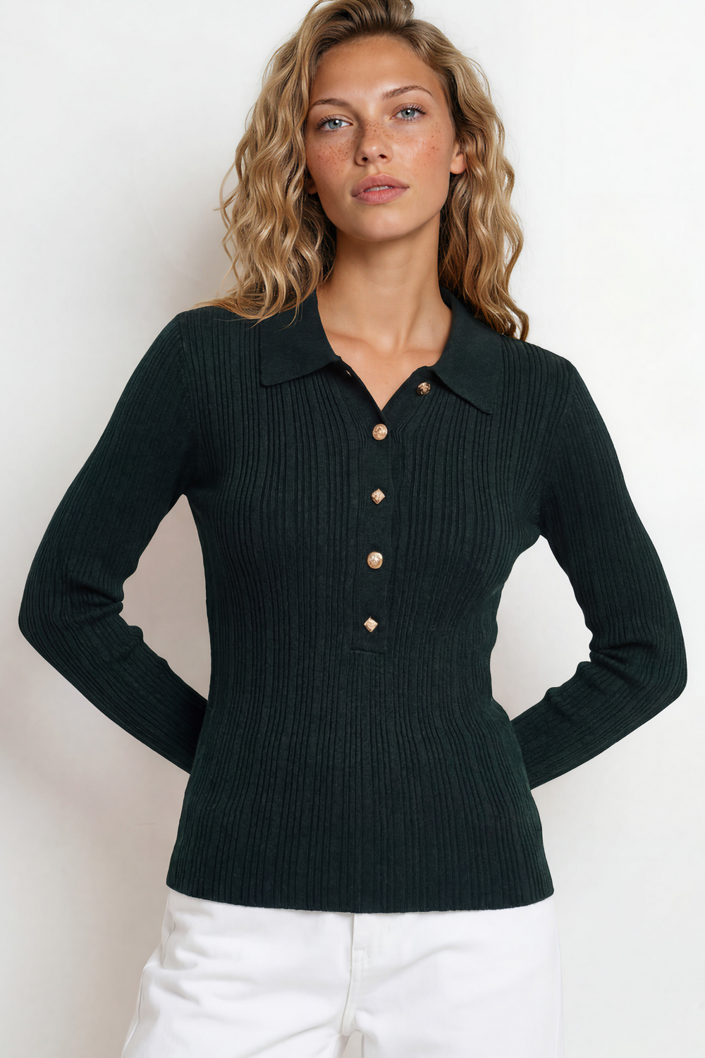 Woman wearing a dark green ribbed sweater with buttons on a white background