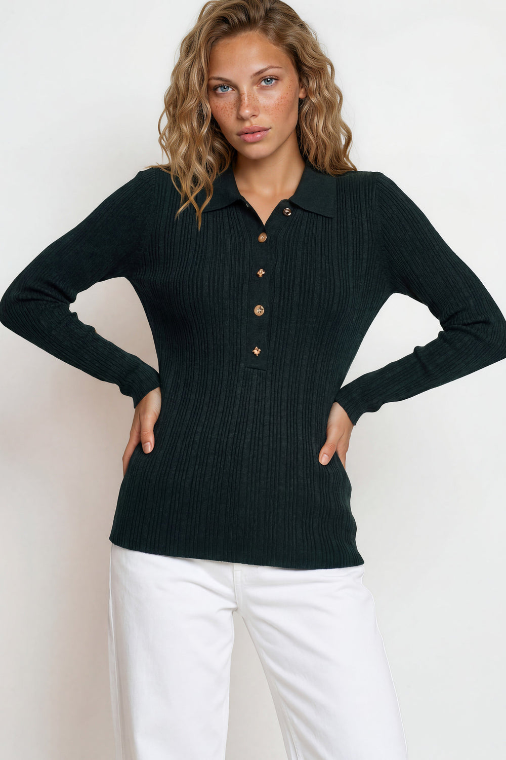Woman wearing a black ribbed sweater with button details against a white background