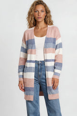 Woman wearing a striped cardigan, white top, and blue jeans against a plain background