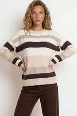 Woman wearing a striped sweater and brown pants against a white background