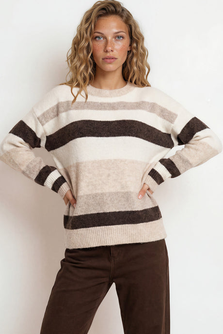 Woman wearing a striped sweater and brown pants against a white background