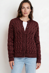 Woman wearing a brown cable knit sweater and light blue jeans on a white background