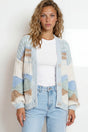 Woman wearing a patterned cardigan and jeans against a plain background