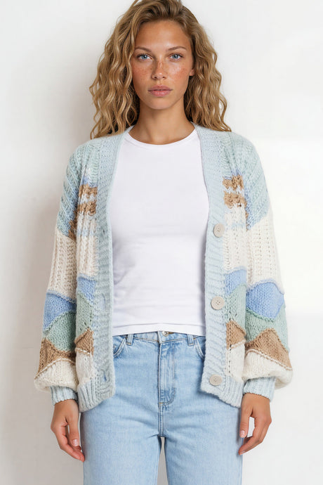 Woman wearing a patterned cardigan, white shirt, and light blue jeans on a plain background