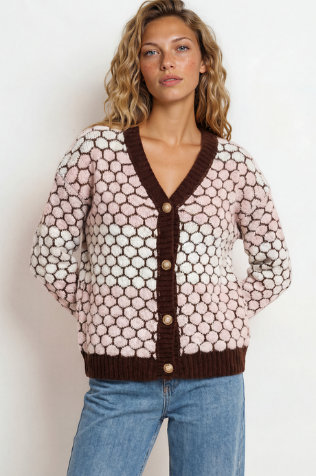 Woman wearing a patterned cardigan with brown trim against a white background