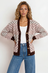 Woman wearing a patterned cardigan with brown trim on a white background
