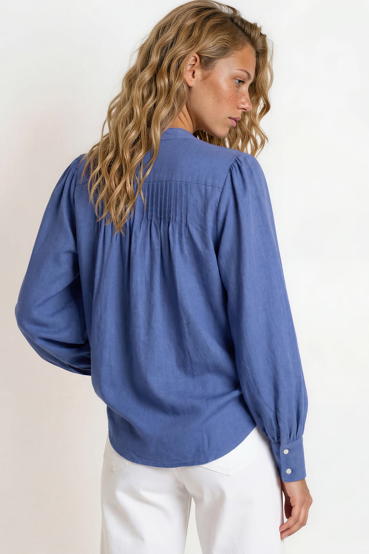 Woman wearing a blue blouse with puffed sleeves against a white background