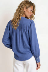 Woman wearing a blue blouse with puffed sleeves against a white background