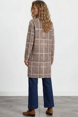 Woman wearing a plaid coat and blue pants against a white background