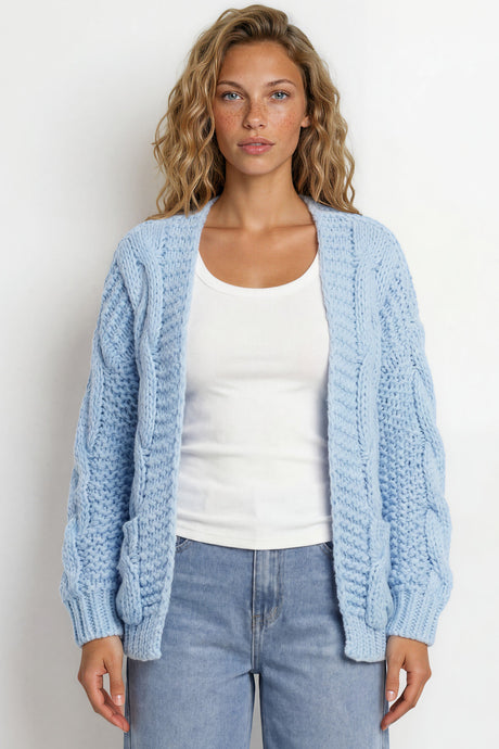 Woman wearing a light blue cardigan over a white top and jeans against a white background