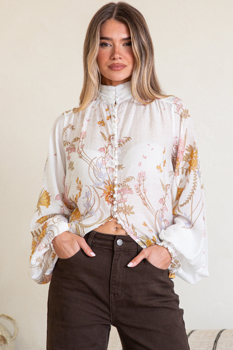 Woman wearing a floral blouse with a neutral background
