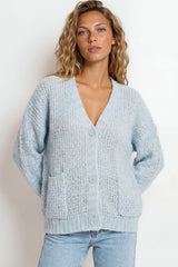 Woman wearing a light blue textured cardigan against a white background