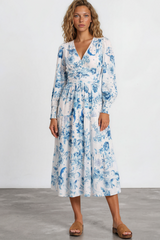 Woman wearing a blue and white floral dress on a plain background
