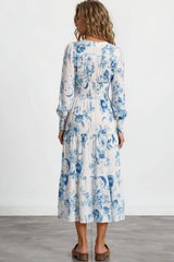 Woman wearing a white dress with blue floral pattern on a plain background