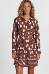 Woman wearing a brown patterned dress on a plain background