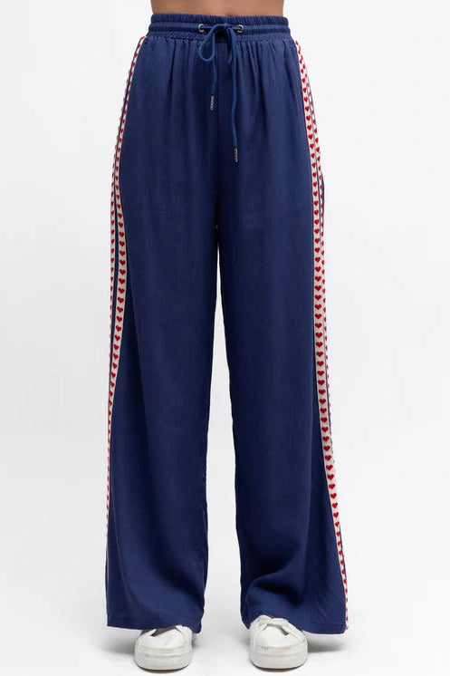 Navy blue pants with red and white striped sides on a white background