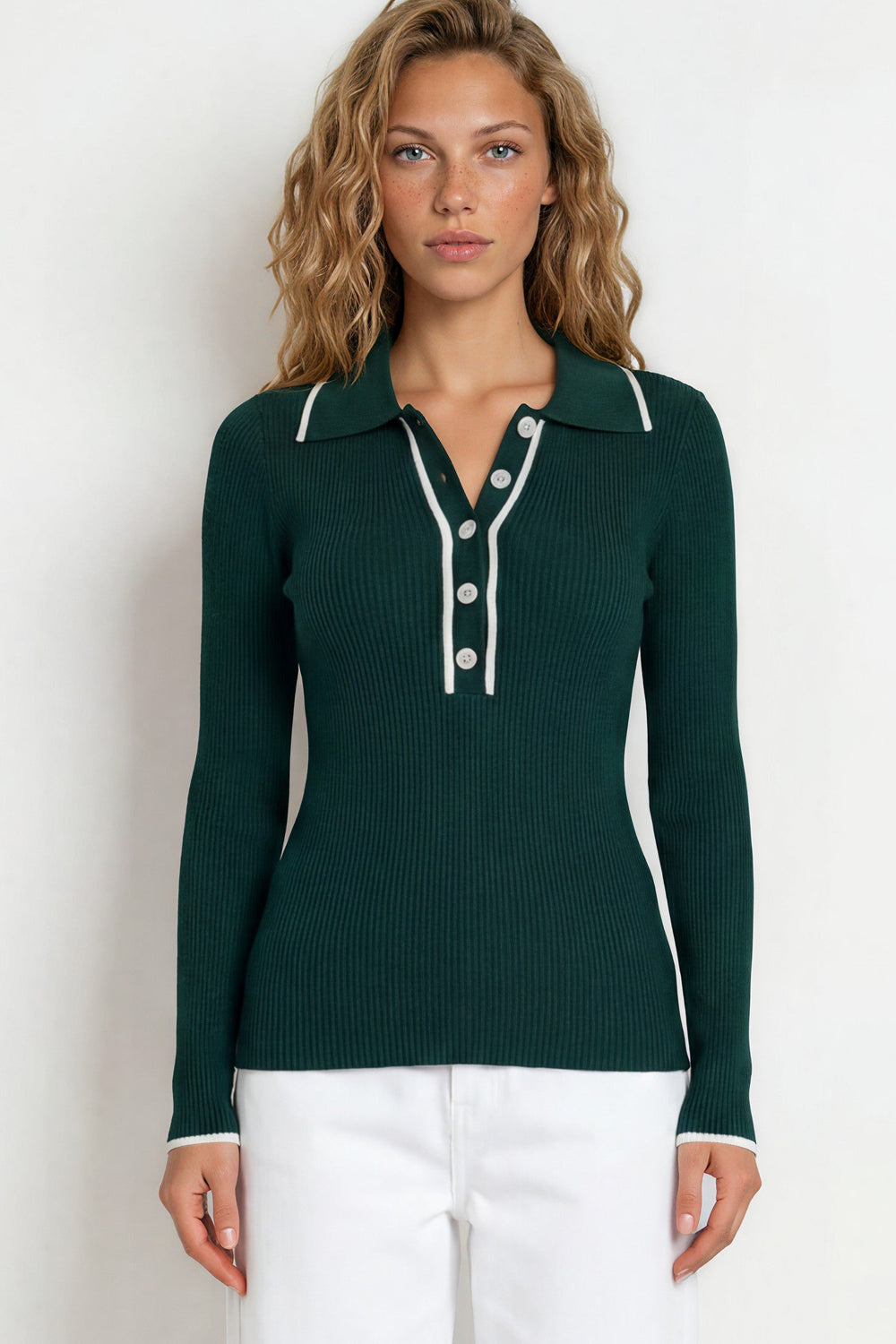 Woman wearing a green long-sleeve shirt and white pants on a white background