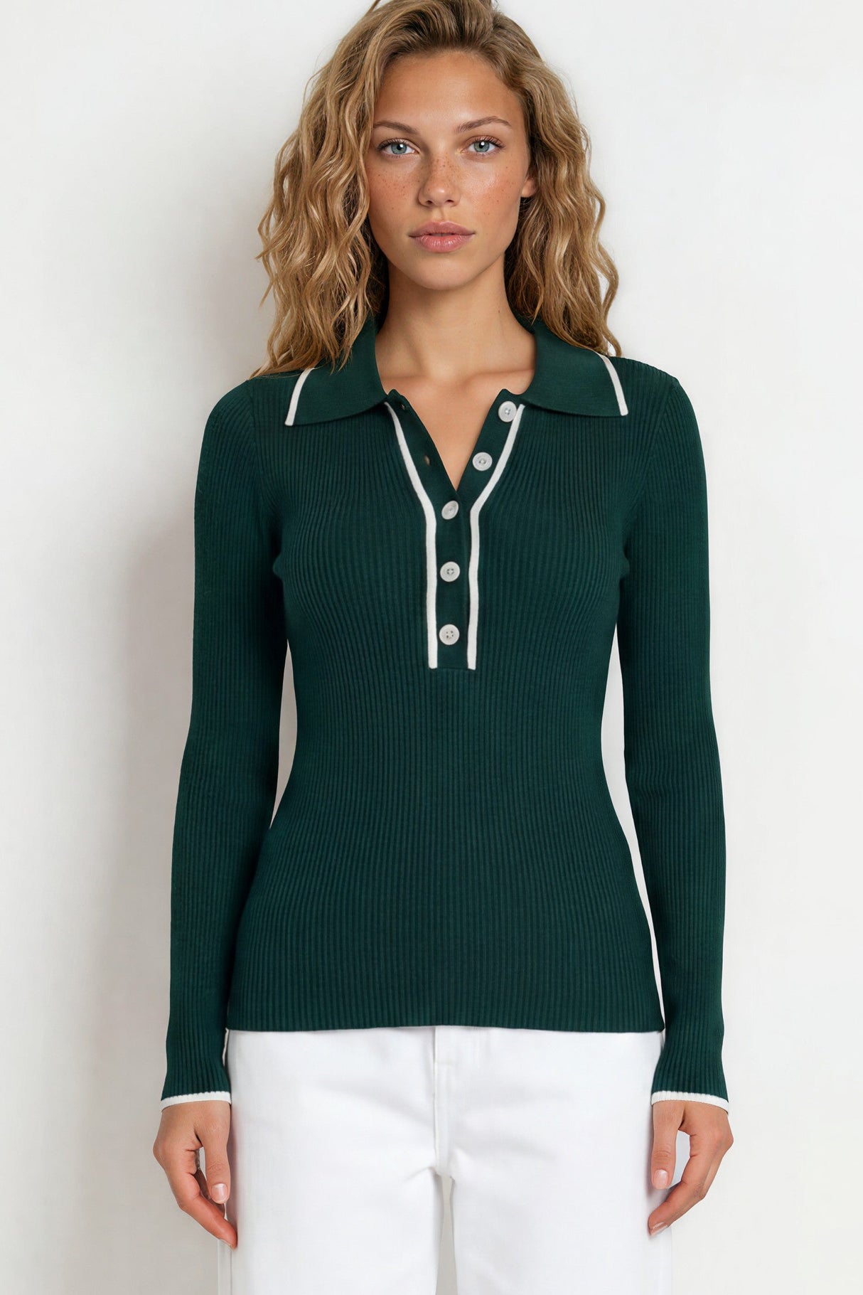 Woman wearing a green long-sleeve shirt and white pants on a white background