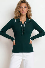 Woman wearing a green long-sleeve polo shirt with white buttons against a plain background