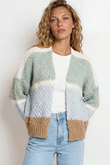 Woman wearing a patterned cardigan with beige accents on a plain background