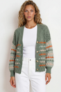 Woman wearing a green patterned cardigan over a white shirt and pants on a white background
