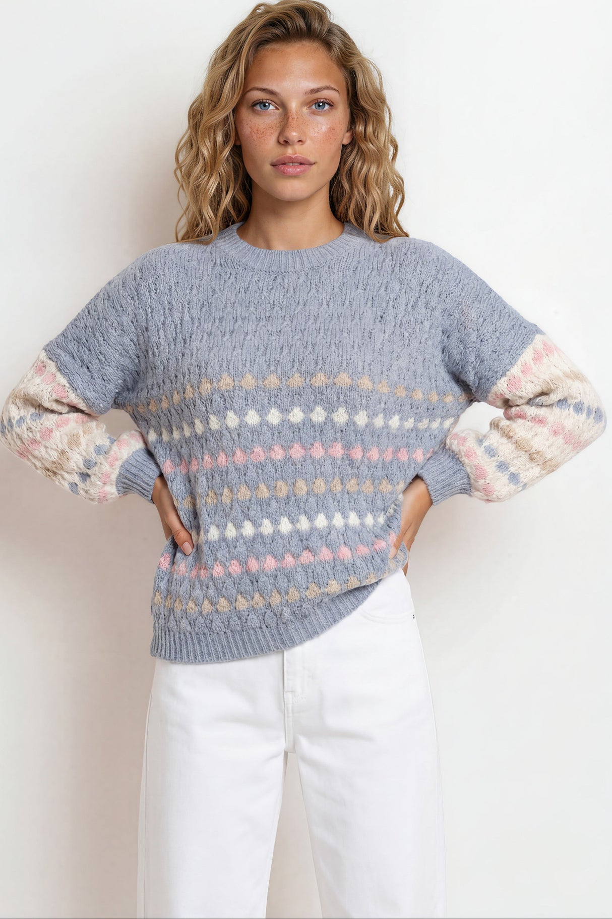 Woman wearing a patterned sweater with pastel sleeves against a white background