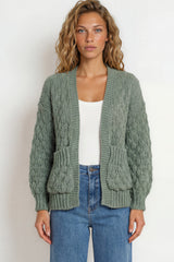 Woman wearing a green knitted cardigan and blue jeans on a white background