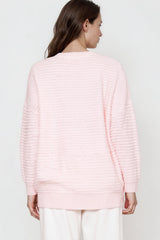 Person wearing a light pink sweater against a plain background