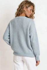 Woman wearing a light blue sweater against a white background