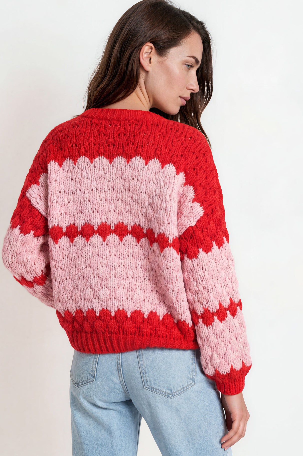 Woman wearing a red and pink striped sweater against a white background