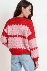 Woman wearing a red and pink striped sweater against a white background