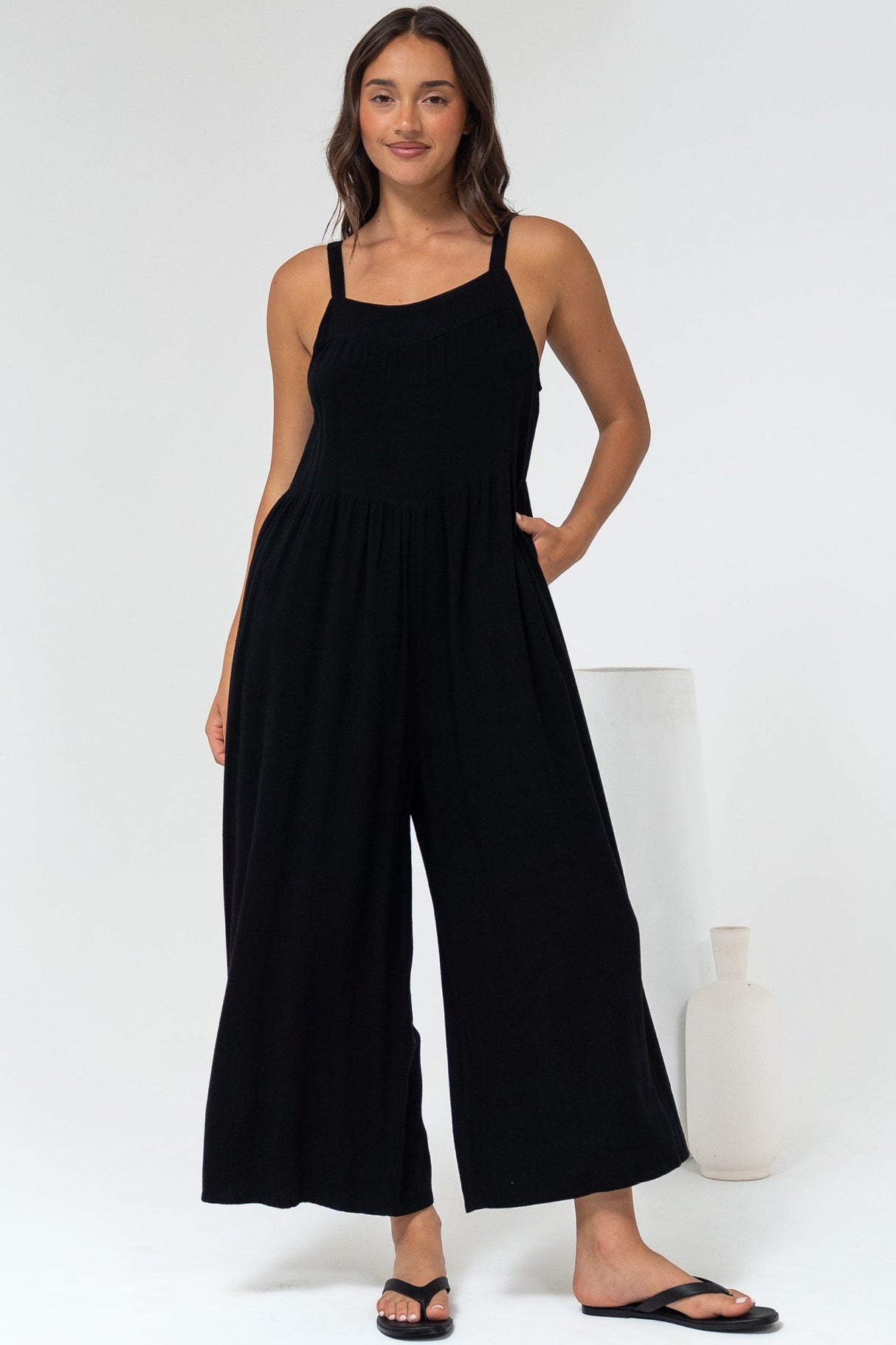 Woman wearing a black jumpsuit standing against a white background