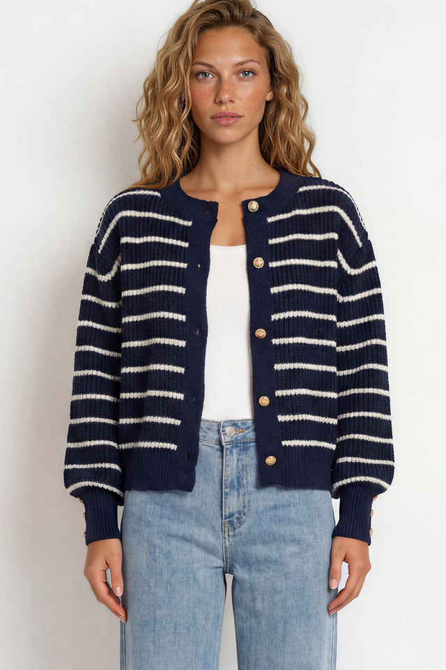 Woman wearing a navy and white striped cardigan with light blue jeans on a white background